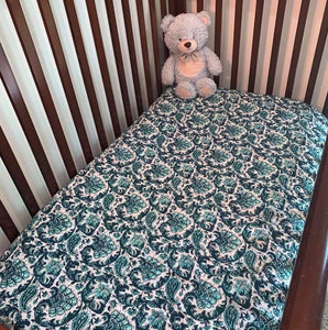 Green baby bedspread in cot