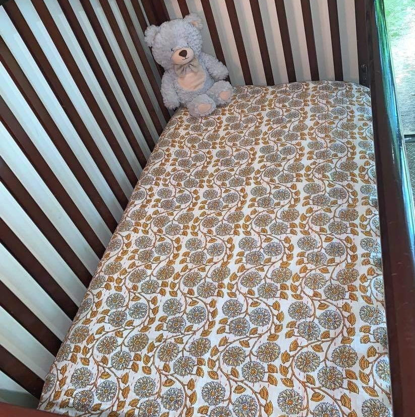 Orange baby bedspread in cot